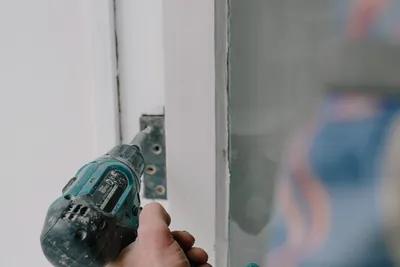 A joiner fitting a new wooden window frame with a cordless screwdriver
