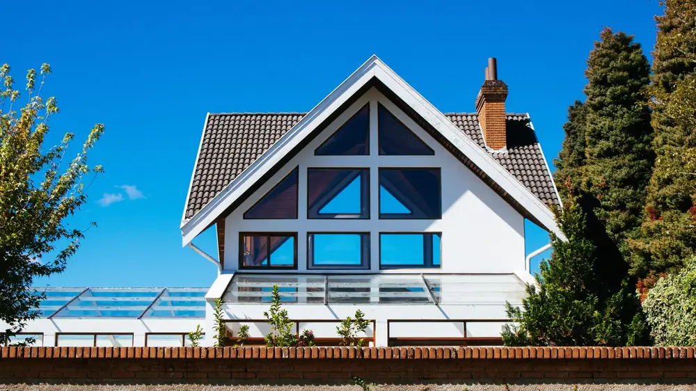 A house with floor-to-ceiling glazing across its gable end on a clear day